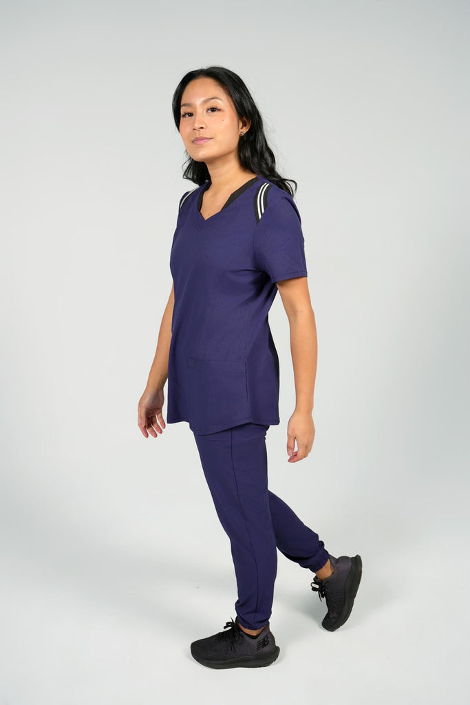 Women's Active Striped Scrub Top in navy side view worn by model with navy scrub jogger pants