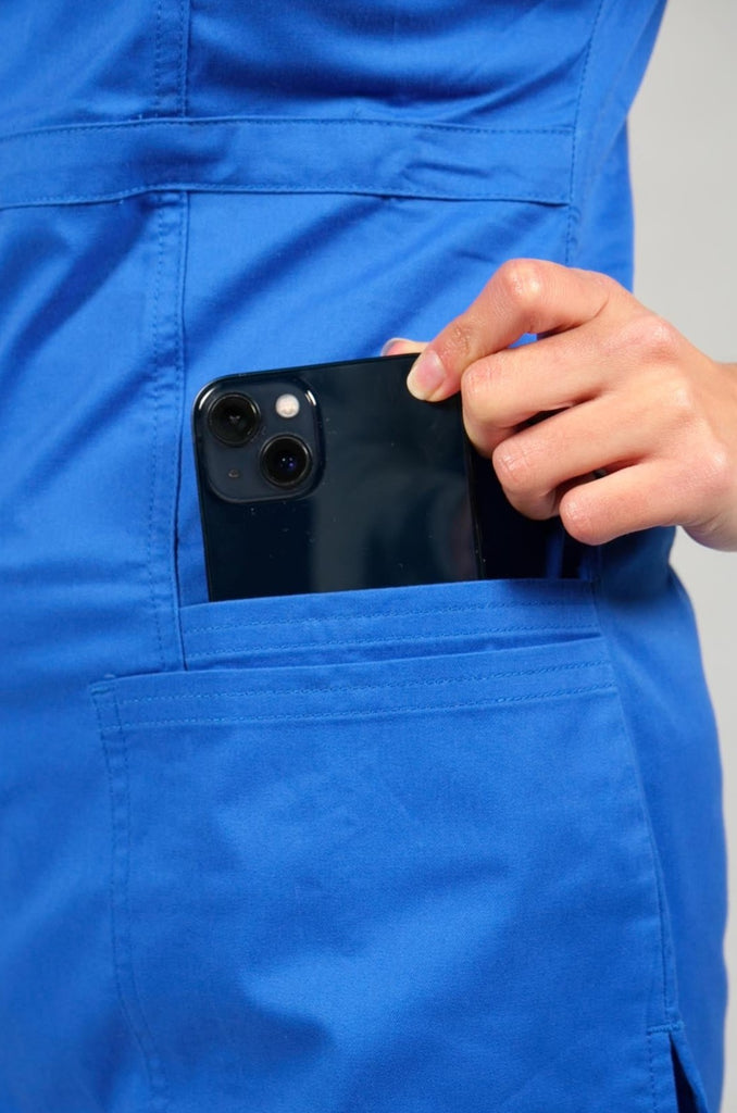 woman pulling phone out of pocket of royal blue scrub top