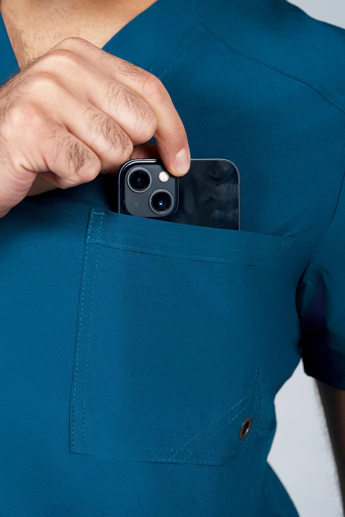 Men's Performance Scrub Top in Caribbean model pulling phone out of pocket