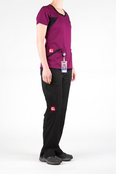 Women's Ultra Flex 4-pocket Scrub Top in wine on model wearing black flex scrub pants side view with id badge hanging from utility loop