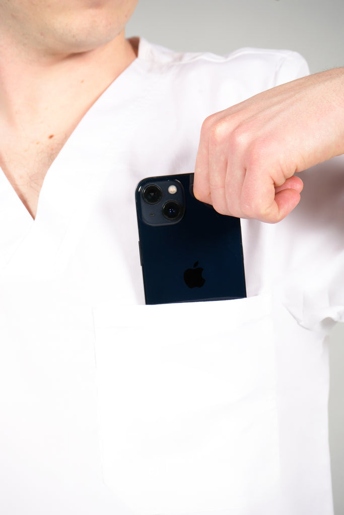 Men’s 2-Pocket V-Neck Scrub Top in White model pulling phone out of pocket