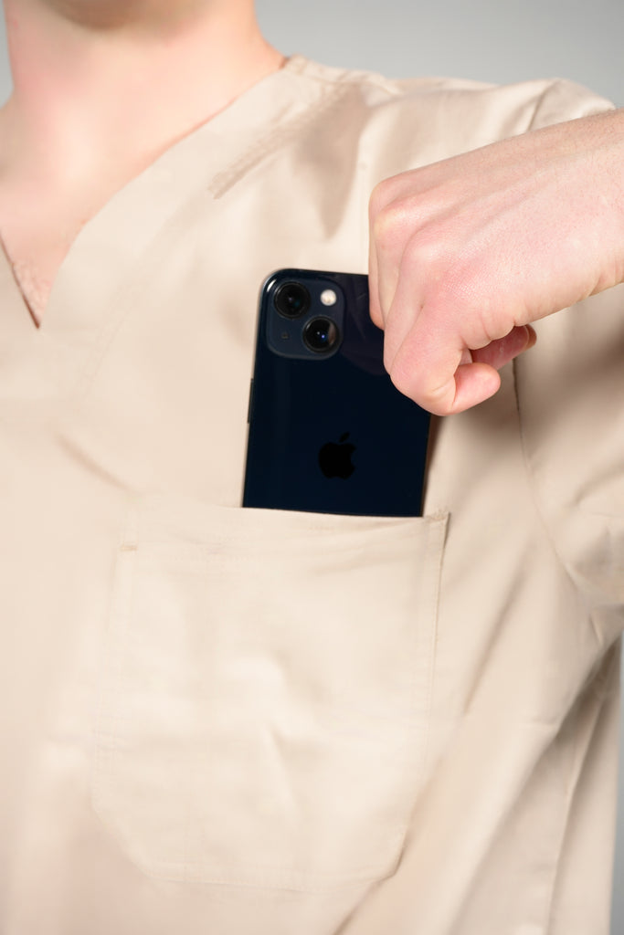 Men’s 2-Pocket V-Neck Scrub Top in Beige model pulling phone out of pocket
