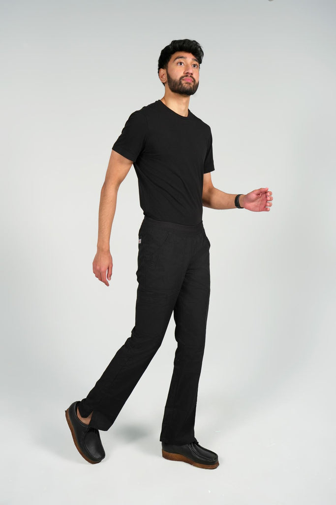 Men's 6-Pocket Elastic Scrub Pant in black side view on model wearing black top