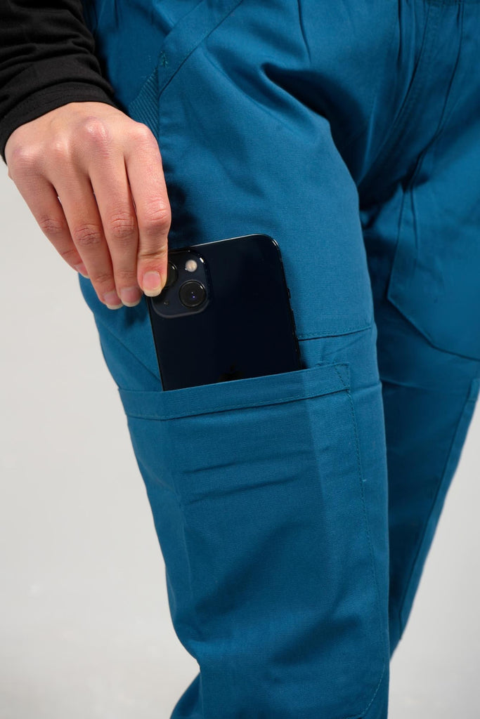 Women's 6-Pocket Elastic Scrub Pant in Caribbean closeup on model putting phone into pocket