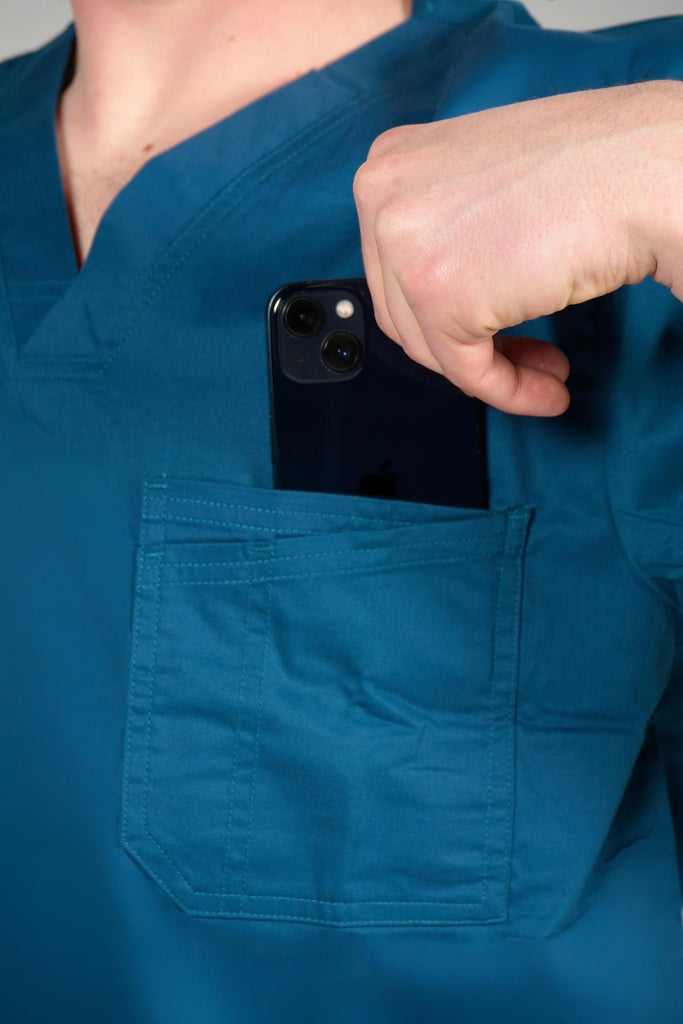 Men's 2-Pocket V-Neck Scrub Top in Caribbean model putting phone into top chest pocket