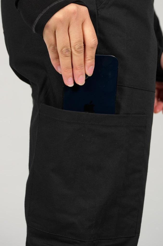 Women's 6-Pocket Elastic Scrub Pant in Black closeup on model putting phone into pocket