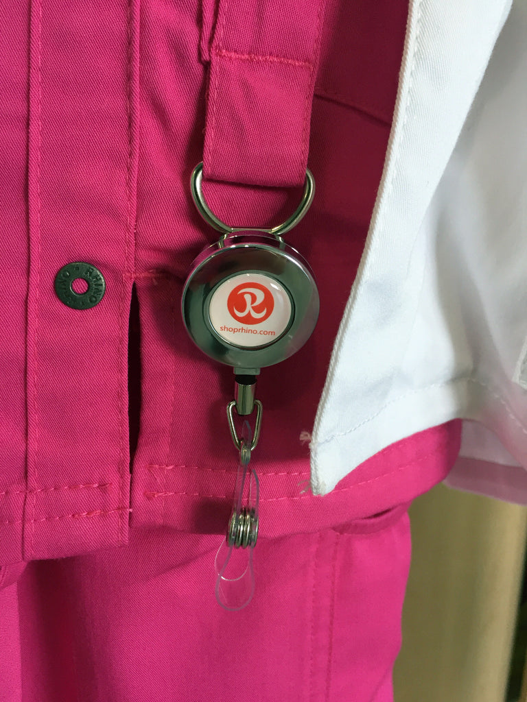 Retractable ID Badge Reel with rhino logo hanging on pink scrub utility loop