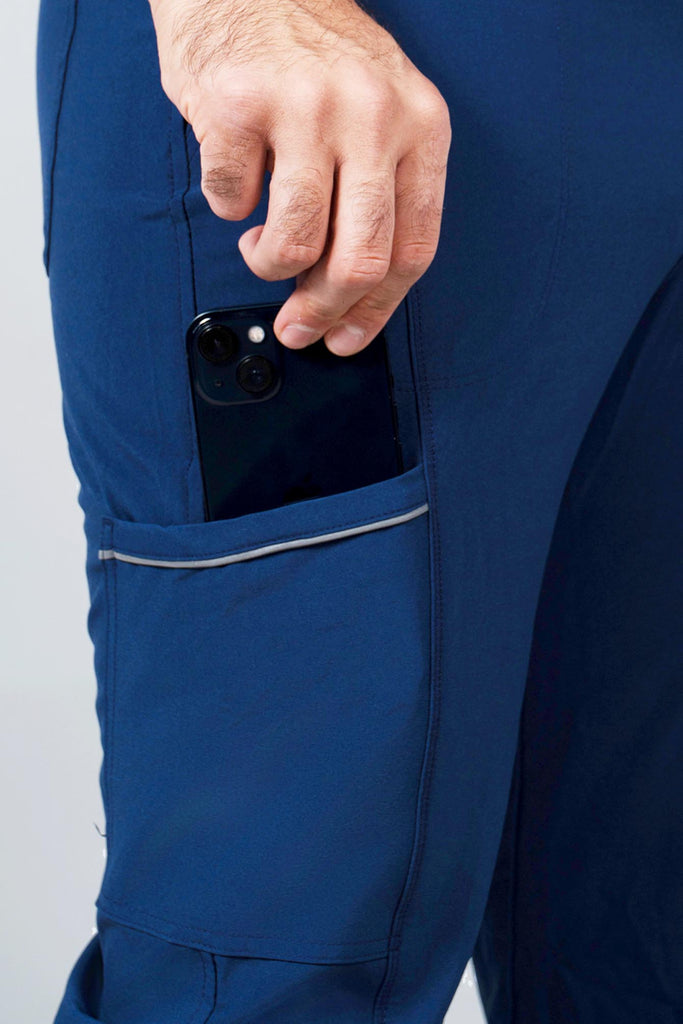 Men's Performance Scrub Jogger in shade navy with model putting phone into pocket