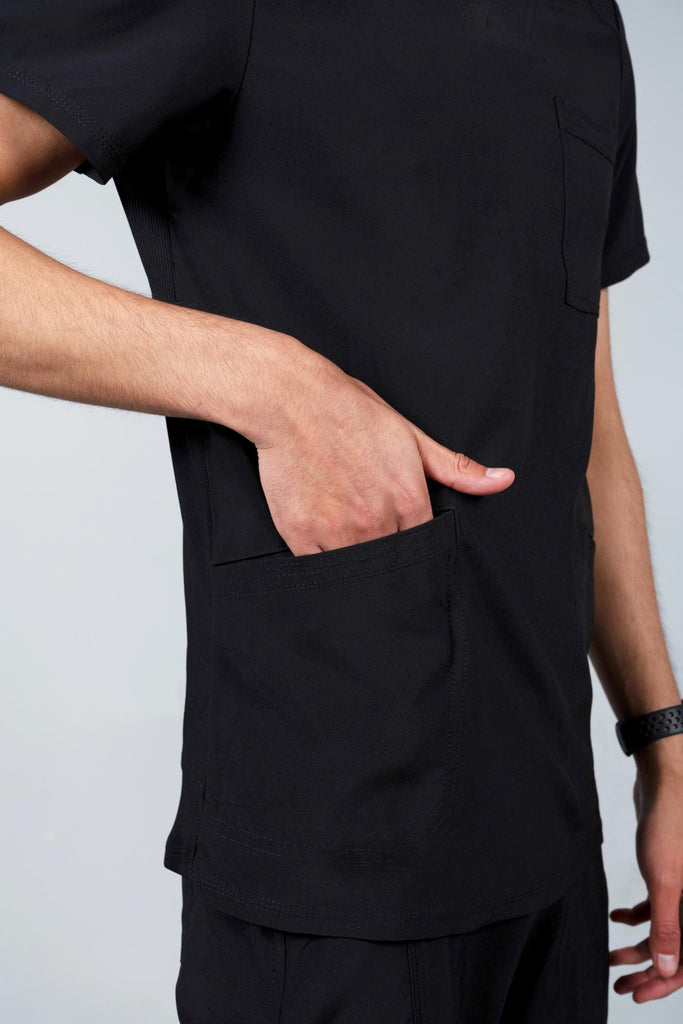 Men's Performance Scrub Top in black model reaching into angled bottom pocket